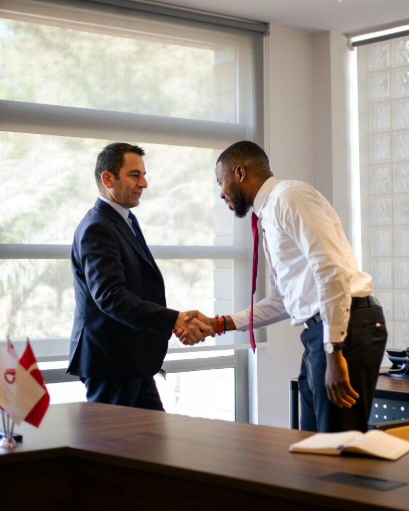 Two business professionals shaking hands across a desk after a wholesale partnership inquiry