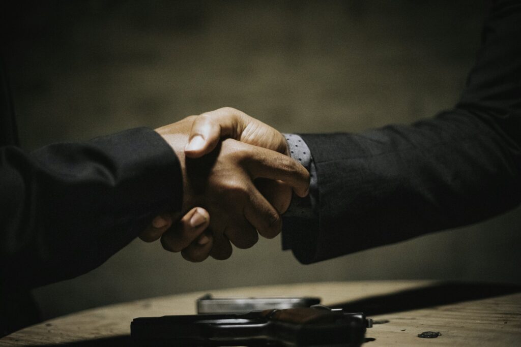 Supplier and buyer shaking hands over a wooden meeting table