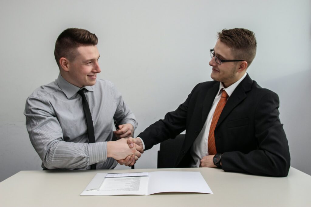 Two business partners shaking hands and smiling after agreeing a wholesale partnership